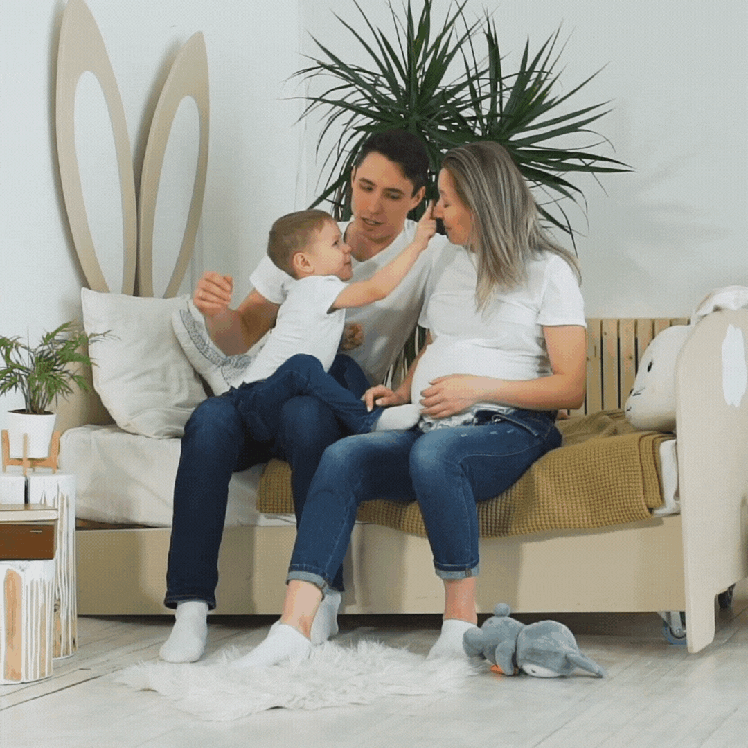 The parents are beaming with joy as they cradle the baby bump, while their first child looks on with excitement.
